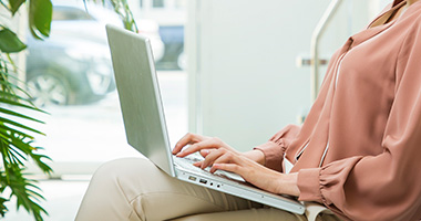 노트북으로 타이핑을 하며 앉아있는 여성의 모습